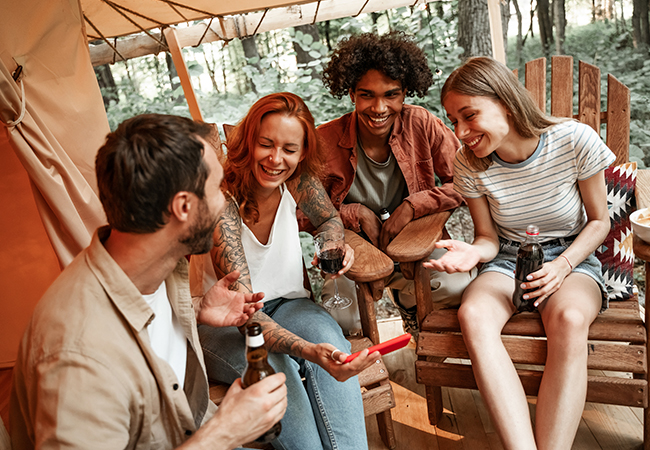 Happy group of young people drinking wine beer using phones social media during picnic in forest Premium Photo